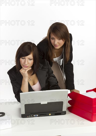 Two young women in an office looking at a laptop