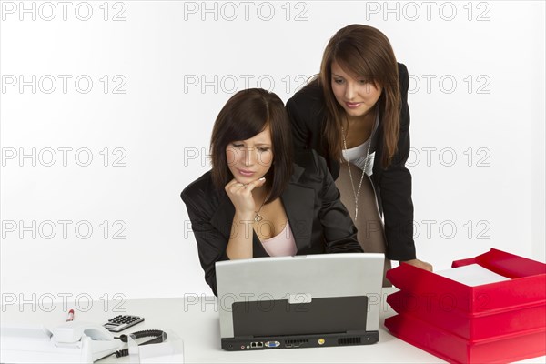 Two young women in an office looking at a laptop