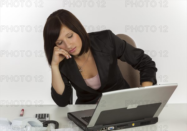 Young woman with a laptop sitting at a desk and sleeping