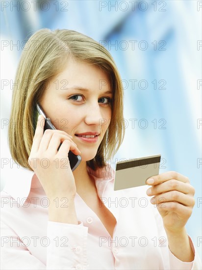 Businesswoman using a mobile phone and holding a card