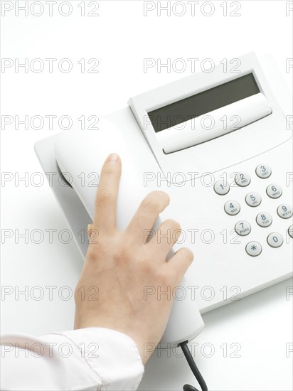 Woman hanging up the handset of a telphone