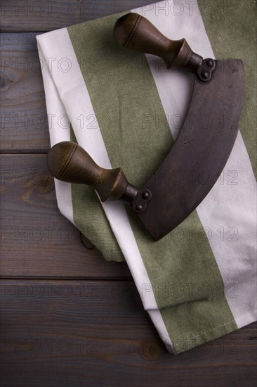 Old chopping knife with a kitchen towel on a wooden background