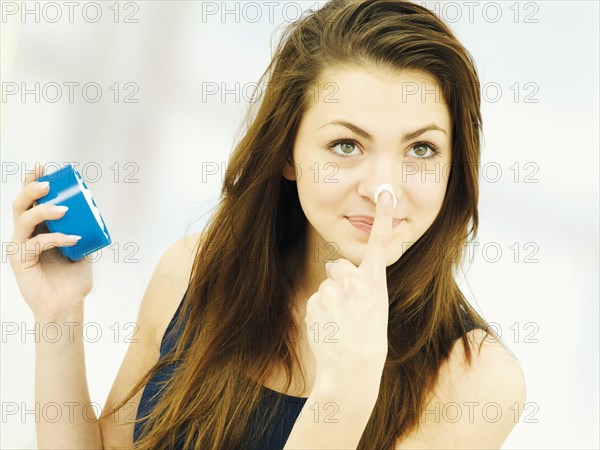 Girl applying cream to her nose