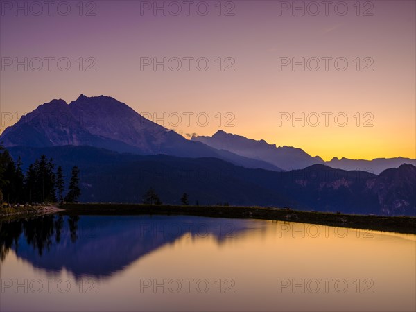 Mountain silhouettes reflected in an artificial mountain lake at sunset