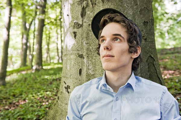 Young man sitting in front of a tree in the woods