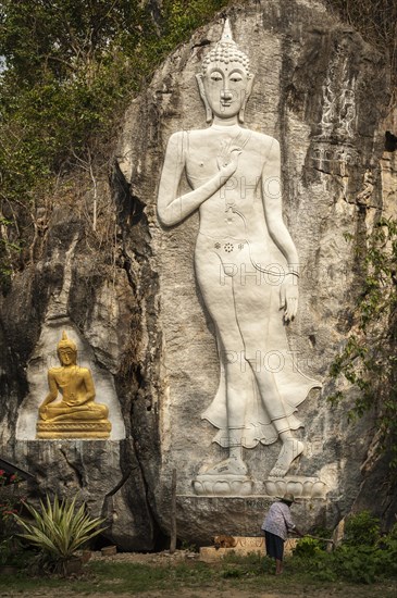 Elderly woman standing in front of a Buddha sculpture