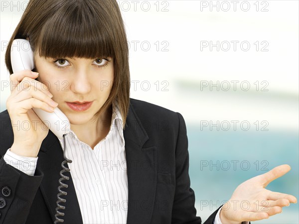 Businesswoman gesticulating while talking on the telephone with an expression of cluelessness