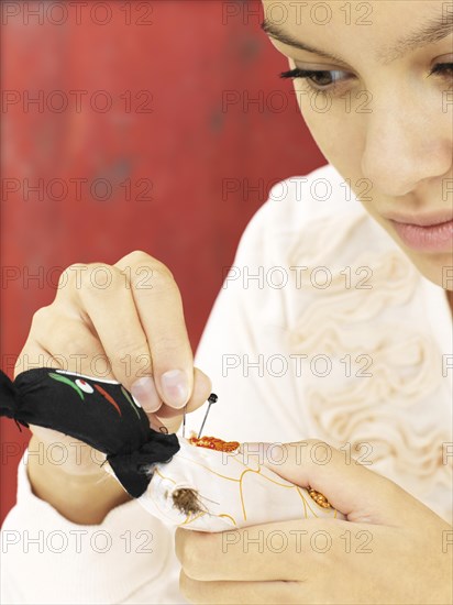 Woman sticking needles into a voodoo doll