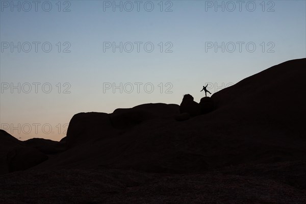 Young man jumping on a granite rock