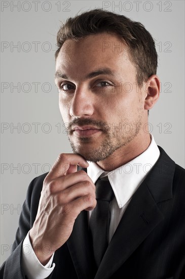 Young businessman wearing a suit with his hand on his chin