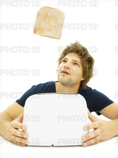 Young man looking at a slice of toast as it pops out of a toaster