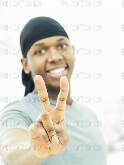 Dark-skinned man wearing a bandana and making a victory sign