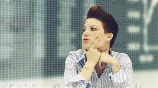 Business woman with a punk hairstyle in front of a stock exchange board