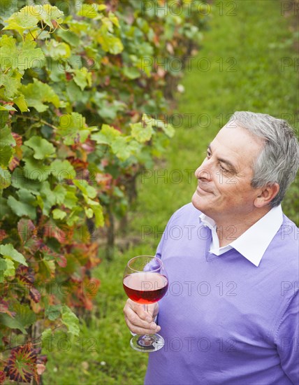 Winemaker or vintner holding a glass of wine in his vineyard