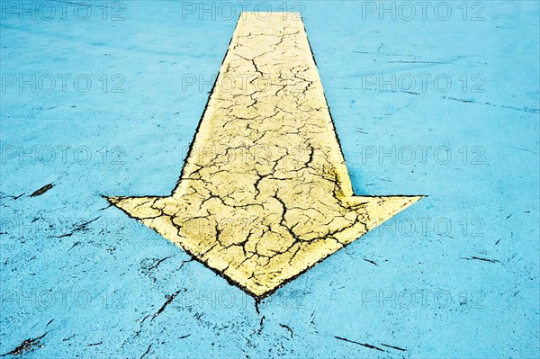 Yellow arrow on blue asphalt
