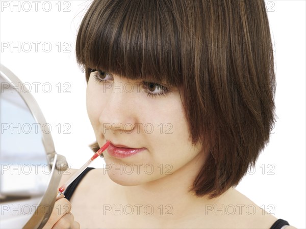 Young woman applying lip gloss