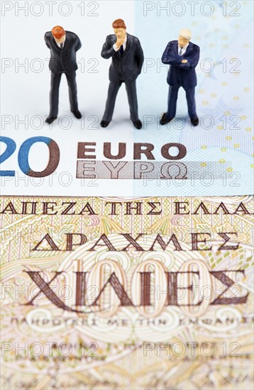 Miniature figurines of businessmen on euro and Greek drachma banknotes