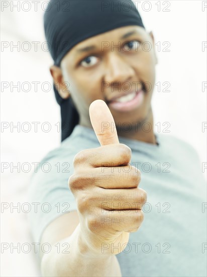 Dark-skinned man man wearing a bandana and making a thumbs up gesture