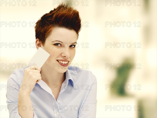 Businesswoman with a punk hairstyle holding a blank business card