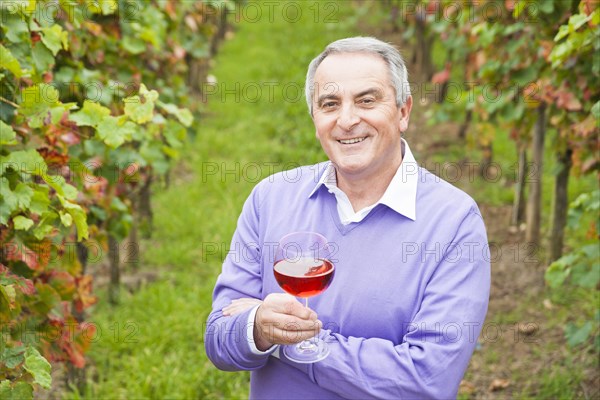 Winemaker or vintner holding a glass of wine in his vineyard