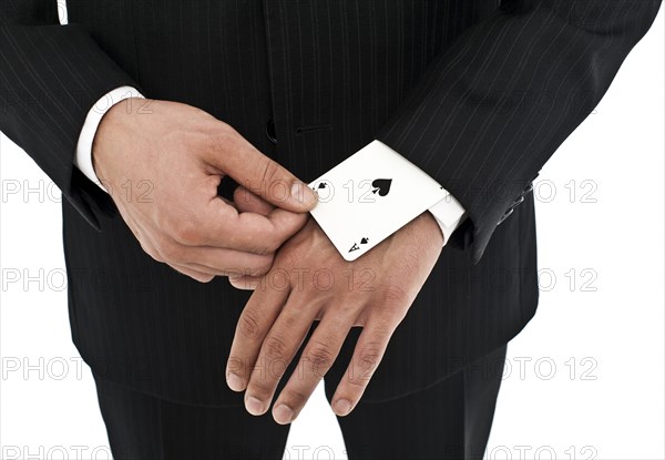 Man wearing a suit pulling an ace of spades out of his sleeve