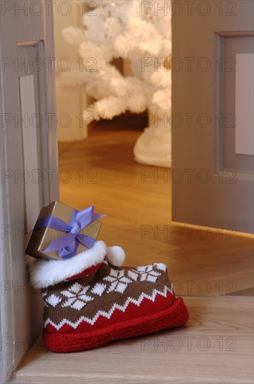 Woolly slipper with Norwegian pattern and present outside an open door