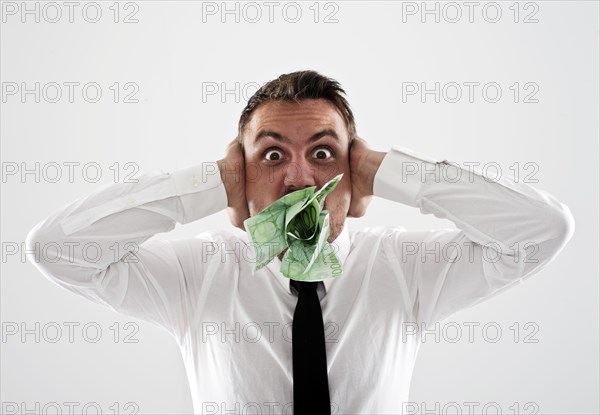 Desperate young man wearing a shirt and a tie holding his hands over his ears