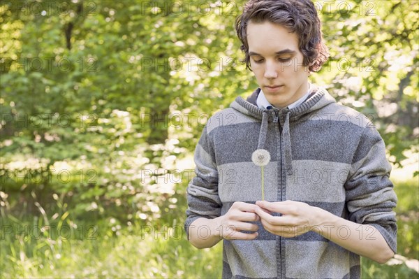 Young man holding dandelion clock