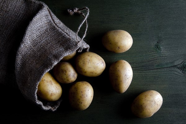 Potatoes in burlap sack on wood