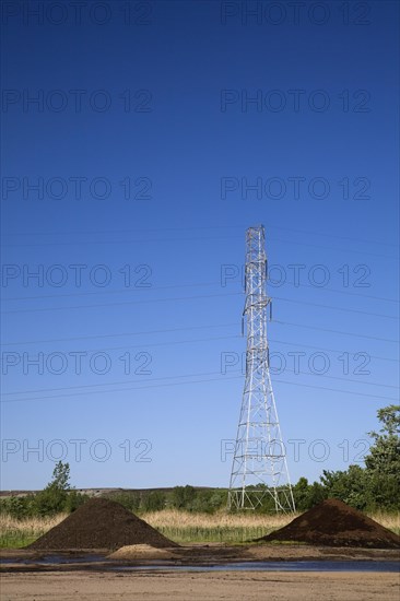 Mounds of topsoil and a hydro electricity transmission tower in a commercial sandpit