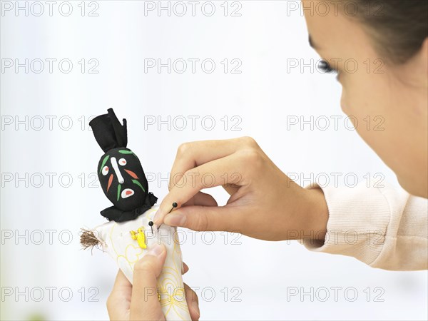 Woman sticking needles into a voodoo doll