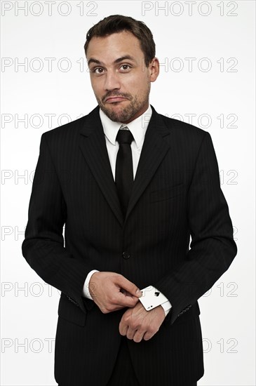 Man wearing a suit pulling an ace of spades out of his sleeve