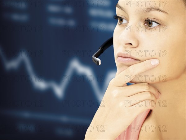 Businesswoman wearing a headset in front of a stock market curve