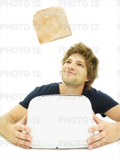 Young man looking at a slice of toast as it pops out of a toaster