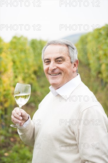 Winemaker or vintner holding a glass of wine in his vineyard