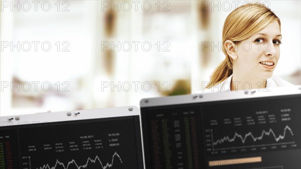 Businesswoman behind monitors with stock exchange rates
