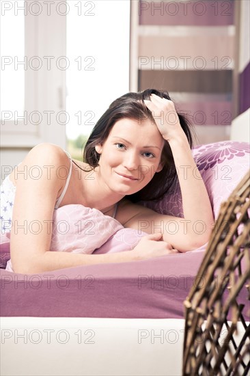 Young woman lying in bed in a bedroom