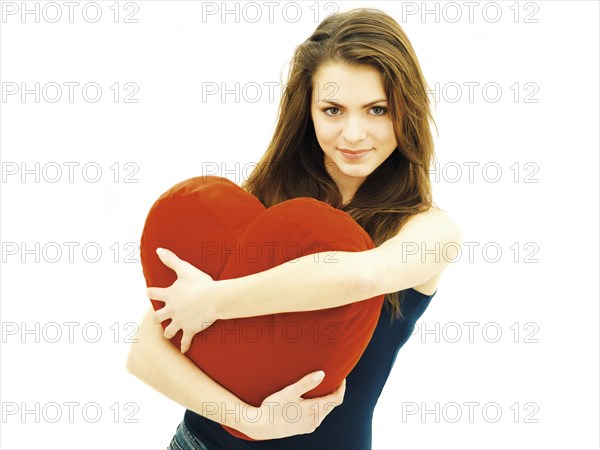 Young woman holding a heart-shaped pillow