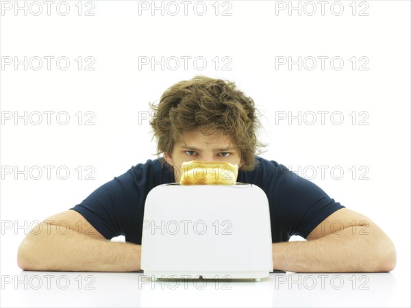 Young man behind a toaster with slices of toast