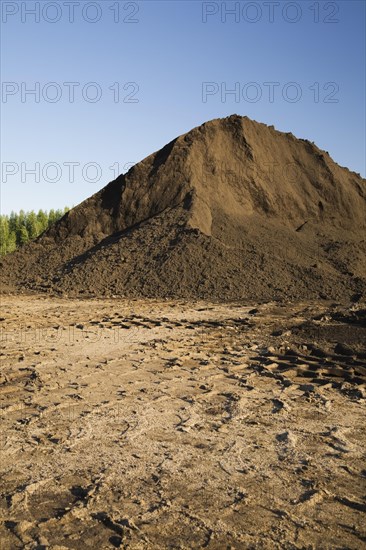 Heavy tire tracks and a mound of topsoil in a commercial sandpit