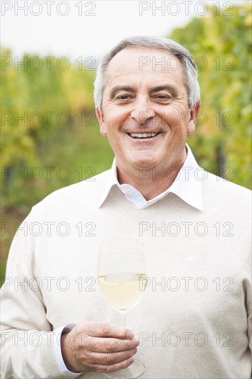 Winemaker or vintner holding a glass of wine in his vineyard