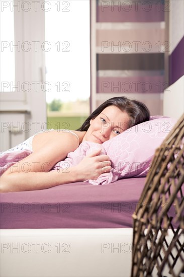Young woman lying in bed in a bedroom