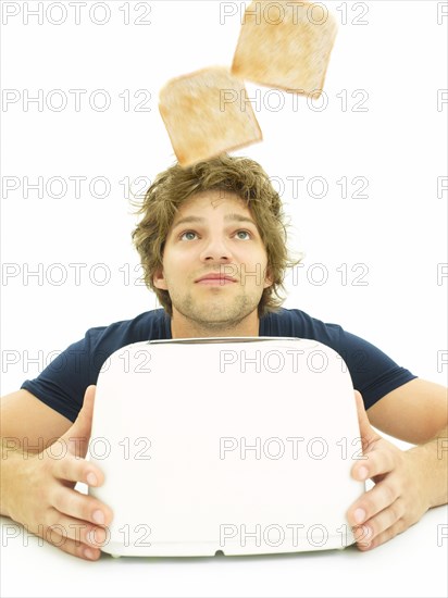 Young man looking at slices of toast as they pop out of a toaster