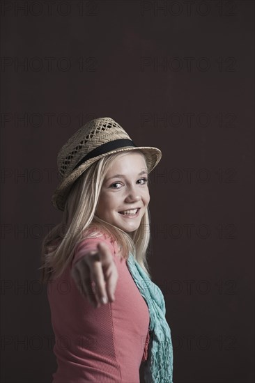Smiling teenage girl wearing a hat pointing towards the camera