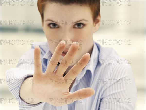 Businesswoman in an office making a defensive gesture with a raised hand