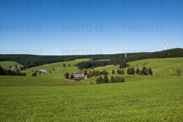 Windmills and farms with solar panels in hilly landscape