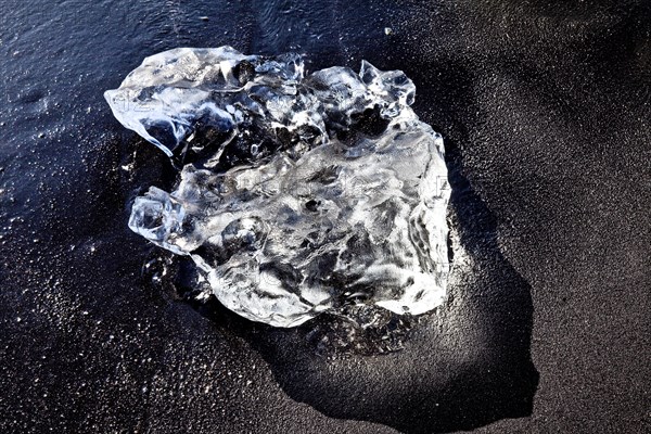 Glacier ice piece on black basalt beach