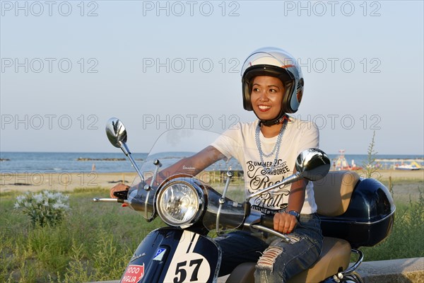 Woman on Vespa 125 Primavera in the port of Penelope