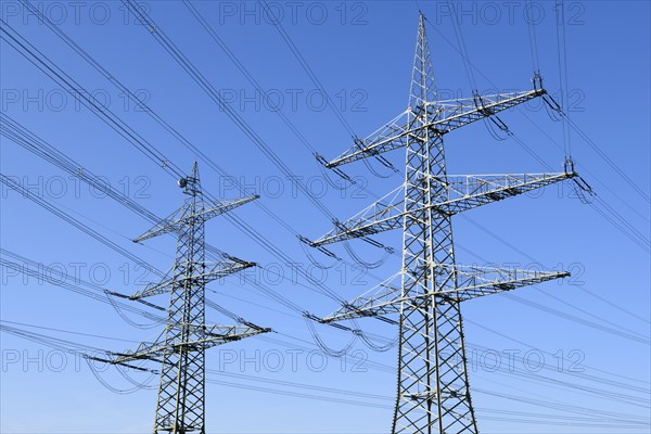 High-voltage pylons in front of a blue sky