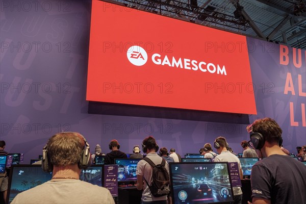 Visitors play video games under the gamescom logo at gamescom